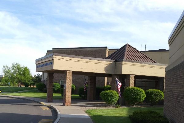 Front entrance of the University of Rochester Highland Living Center at Brighton, featuring a flag atop the building.